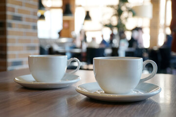 Two white cups on coffee the table in the cafe . Breakfast