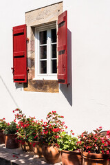 Window with red shutters on the white wall.