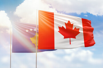 Sunny blue sky and flags of canada and kosovo