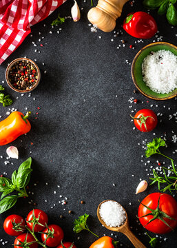 Food frame, ingredients for cooking. Food cooking background on black stone table. Fresh vegetables, herbs and spices. Top view with copy space.