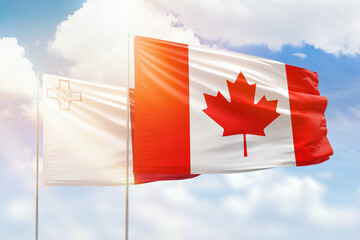 Sunny blue sky and flags of canada and malta