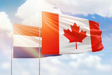 Sunny blue sky and flags of canada and netherlands