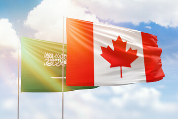 Sunny blue sky and flags of canada and saudi arabia