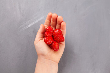 Fresh juicy berries. Unusual organic strawberries in kids palm. Ugly fruits. Concept - Reduce...