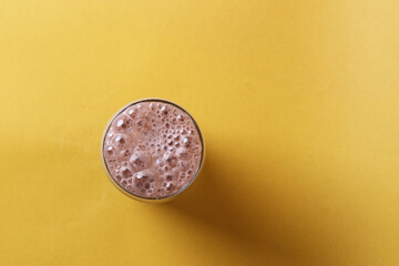 Chocolate milk in glass cup isolated on yellow background