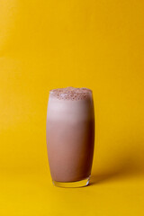 Chocolate milk in glass cup isolated on yellow background