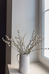 illow branches in a white ceramic jug and a mirrored disco ball on the windowsill as decoration before Easter