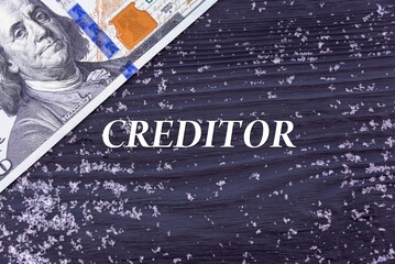 CREDITOR - word (text) on a dark wooden background, money, dollars and snow. Business concept (copy space).