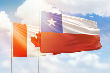 Sunny blue sky and flags of chile and canada