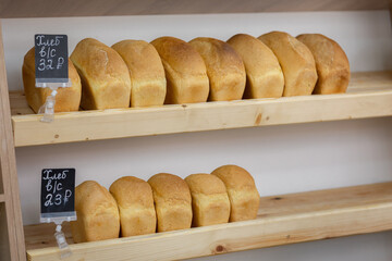 Bricks of wheat bread lie on wooden shelves in store. Fresh delicious of bread loaves in bakery, baker shop. High quality photo