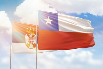 Sunny blue sky and flags of chile and serbia
