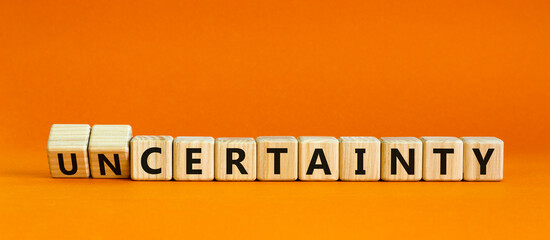 Certainty or Uncertainty symbol. Turned wooden cubes and changed concept words Uncertainty to Certainty. Beautiful orange background. Business and Certainty or Uncertainty concept. Copy space.
