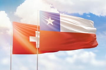 Sunny blue sky and flags of chile and switzerland