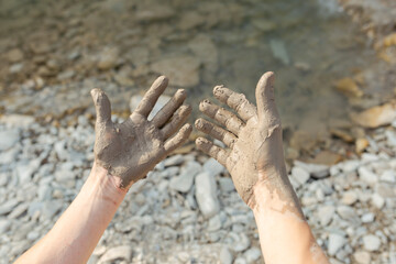 Man's hand smearing black healing mud on the arm. Close-up