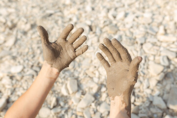 Man's hand smearing black healing mud on the arm. Close-up