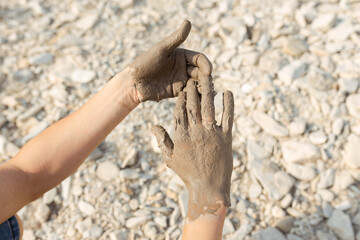 Man's hand smearing black healing mud on the arm. Close-up