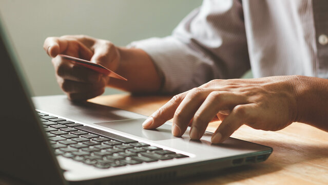 Businessman using laptop computer with a credit card making an online order. Business, online shopping, e-commerce, internet banking, spending money, online payment, working from home concept.