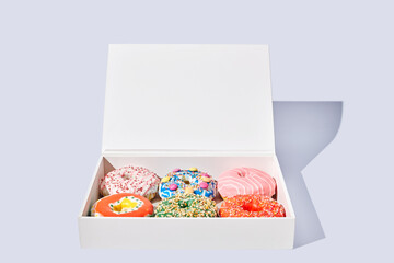 Decorated donuts in a box on white background