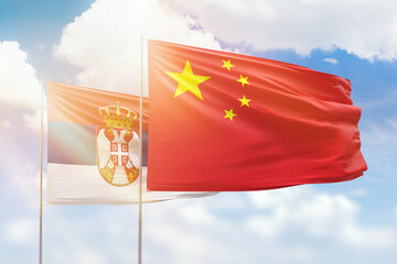 Sunny blue sky and flags of china and serbia