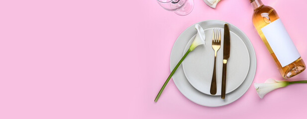 Beautiful table setting with calla lilies and bottle of wine on pink background. Banner for design