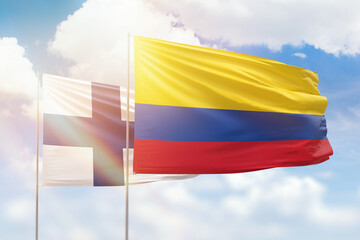 Sunny blue sky and flags of colombia and finland