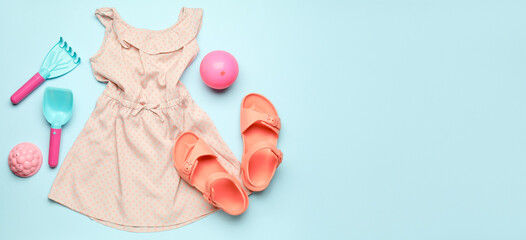 Baby's dress and beach accessories on blue background with space for text
