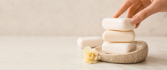 Female hand with soap bars on light background with space for text - obrazy, fototapety, plakaty