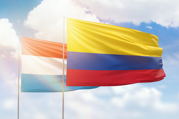 Sunny blue sky and flags of colombia and luxembourg