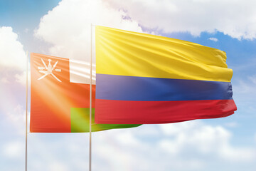 Sunny blue sky and flags of colombia and oman