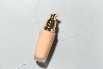 Bottle of makeup foundation in water on grey background