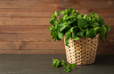 Basket with mint leaves on wooden background