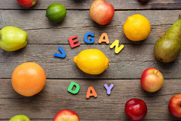 Naklejka na ściany i meble Different scattered fruits and text VEGAN DAY on wooden background