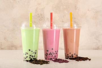 Plastic cups of tasty bubble tea on light table