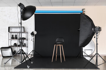 Fototapeta na wymiar Lighting equipment, chair and cyclorama in modern photo studio