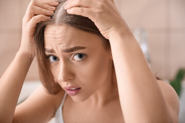 Stressed young woman with hair loss problem  at home