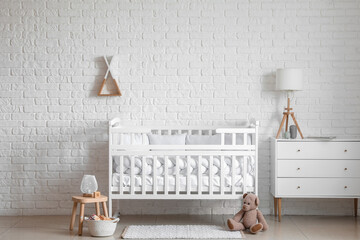 Interior of light nursery with baby crib, chest of drawers and toys