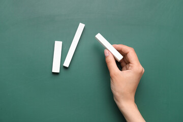 Woman with white chalks on green blackboard, top view