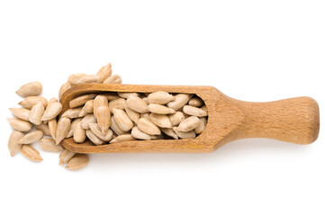 Wooden scoop with peeled sunflower seeds on white background