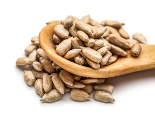 Wooden spoon and peeled sunflower seeds on white background, closeup