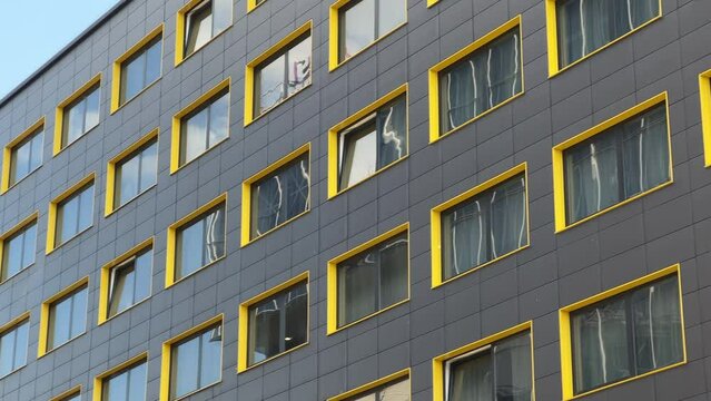 Building facade with black aluminum cladding and yellow and red window slopes