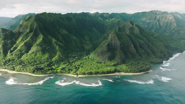 Wonderful fresh deep blue ocean waves at high green peaks formations with steep green walls. Panoramic aerial of scenic tropical Hawaii nature. Cinematic green mountain landscape of wild island nature