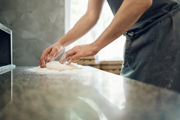 Kitchen chef preparing dough for pizza while working in a pizza place