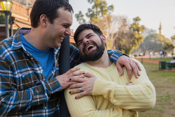 Happy gay couple laughing outdoors. LGBTQ, diversity, inclusive concept. Copy space.	