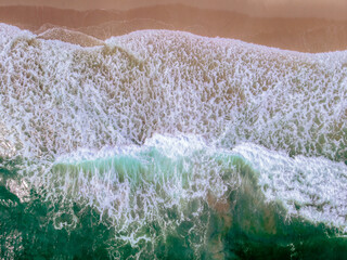 downward drone shot of waves crashing on beach