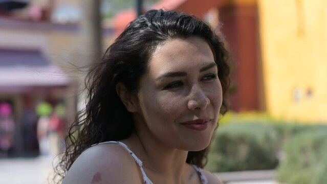 Hermosa mujer latina t&iacute;mida sonriendo en exterior volteando a c&aacute;mara 