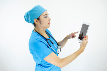 beautiful woman doctor, wearing blue uniform and blue surgical cap, stethoscope on her neck, using the tablet to display results on white background