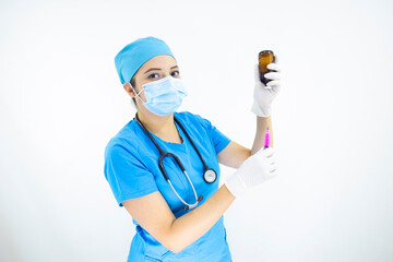 Beautiful woman doctor wearing mask face, uniform and blue surgical cap, stethoscope and latex gloves, preparing injection on white background