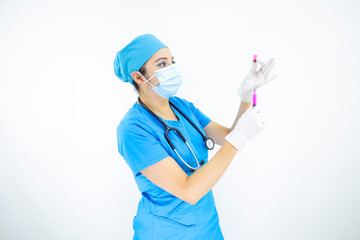 Beautiful woman doctor wearing mask face, uniform and blue surgical cap, stethoscope and latex gloves, preparing injection on white background