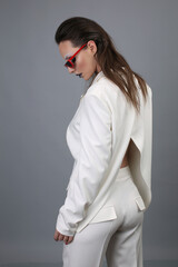 Portrait of a beautiful fashion woman brunette in a white business suit in the studio in a glasses