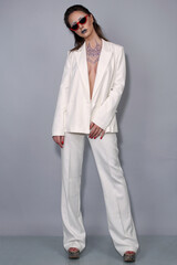 Portrait of a beautiful fashion woman brunette in a white business suit in the studio in a glasses